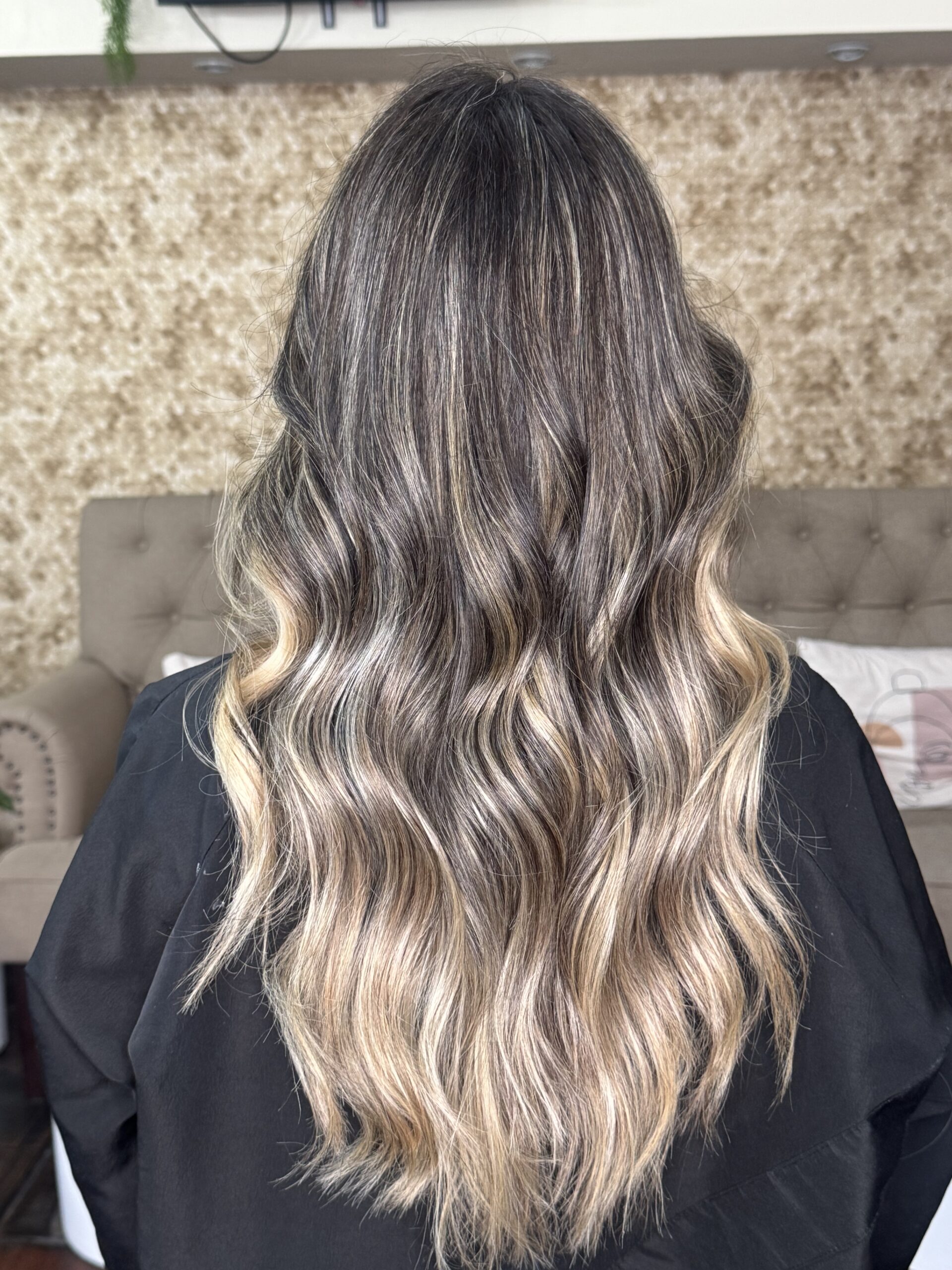 Vista posterior de un balayage rubio beige cenizo con transición sutil desde la raíz