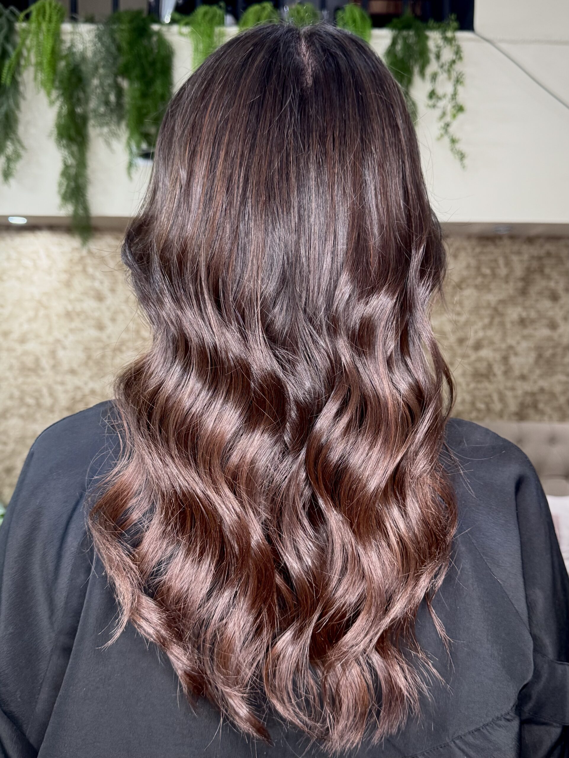 Balayage en tono marrón sin decoloración sobre cabello ondulado, resultado en Moon Salon